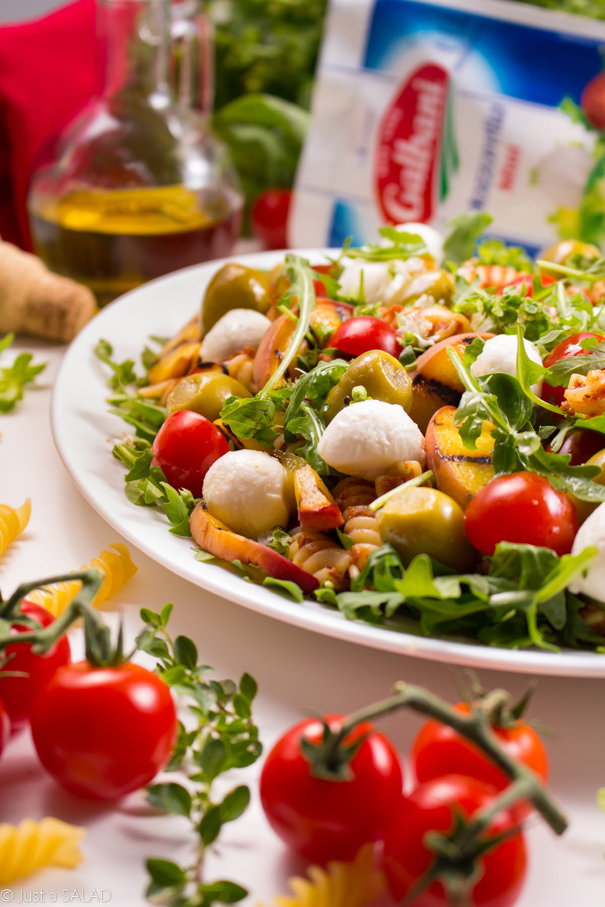 Włoska strona lata. Sałatka z makaronem w pomidorowym pesto, rukolą, pomidorkami, brzoskwiniami, oliwkami i mozzarellą.